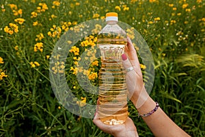 A woman's hand holds a bottle of rapeseed oil