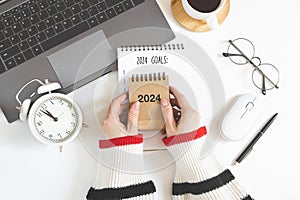 Woman's hand holds calendar, year change from 2023 to 2024.