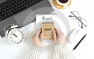 Woman's hand holds calendar, year change from 2023 to 2024.