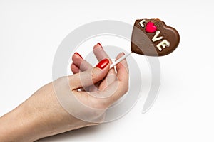 a woman& x27;s hand holds a candy on a stick in the form of a heart