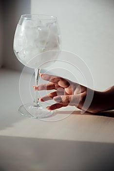 A woman's hand holds a glass with ice
