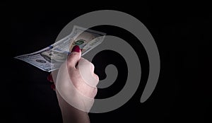 A woman`s hand holds out a dollar bill on a black background