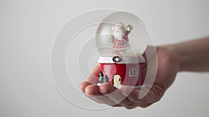 A woman`s hand holds a snow globe with Santa Claus, snow is drunk