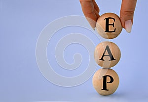 A woman\'s hand holds a wooden ball with the abbreviation EAP