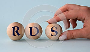 A woman's hand holds a wooden ball with the abbreviation RDS photo