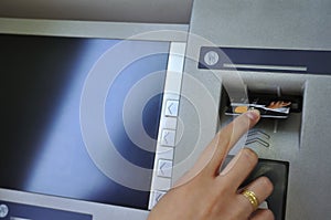 Woman's hand inserting card into cash dispense photo