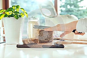 Woman`s hand with kitchen knife cutting homemade healthy bread