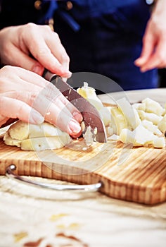 Woman`s hand with a knife cutting the boiling potatoes