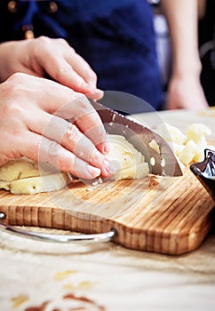 Woman`s hand with a knife cutting the boiling potatoes