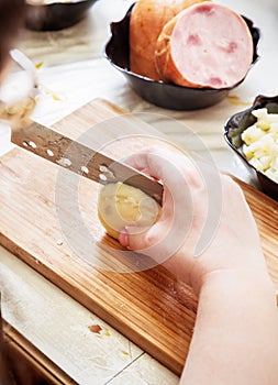 Woman`s hand with a knife cutting the boiling potatoes