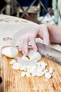 Woman`s hand with a knife cutting the boiling potatoes