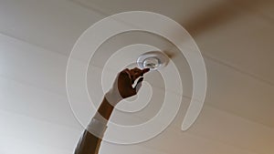 A woman`s hand knocks against energy-saving light bulb to turn on.