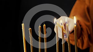 A woman's hand lights candles on the last day of Hanukkah from a shamash candle in a Hanukkah candlestick