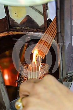 Woman`s hand lit incense stick at oil lamp in a shrine to pray for the gods. Asian beliefs religious ceremony