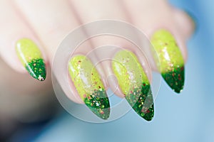 Woman\'s hand with long nails and bright yellow green thermo manicure