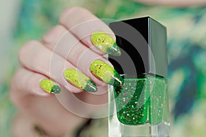 Woman\'s hand with long nails and bright yellow green thermo manicure