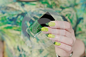 Woman\'s hand with long nails and bright yellow green thermo manicure