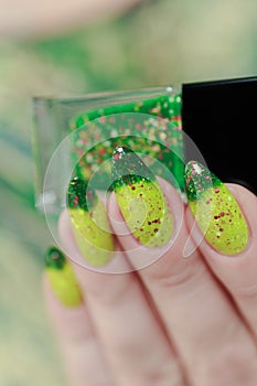 Woman\'s hand with long nails and bright yellow green thermo manicure