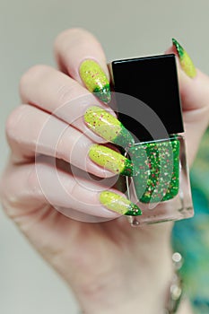 Woman\'s hand with long nails and bright yellow green thermo manicure