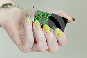 Woman\'s hand with long nails and bright yellow green thermo manicure