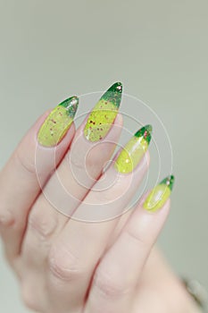 Woman\'s hand with long nails and bright yellow green thermo manicure