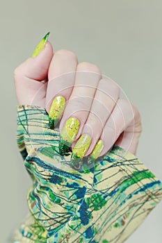 Woman\'s hand with long nails and bright yellow green thermo manicure