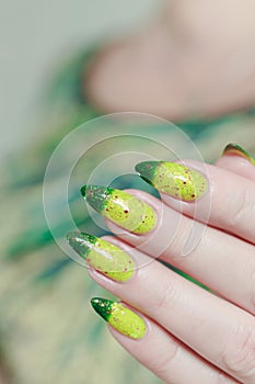 Woman\'s hand with long nails and bright yellow green thermo manicure