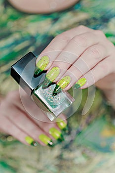 Woman\'s hand with long nails and bright yellow green thermo manicure