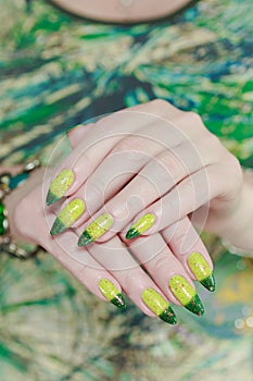 Woman\'s hand with long nails and bright yellow green thermo manicure