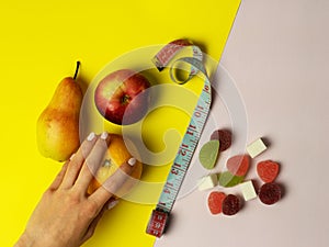 A woman`s hand makes a choice in favor of proper nutrition. on pink and yellow background useful fruits