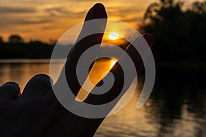 Woman`s hand making peace sign at sunset