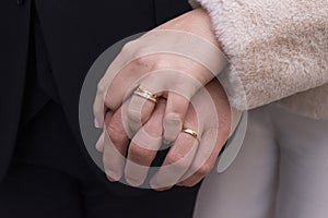 A woman`s hand on a man`s hand with rings.