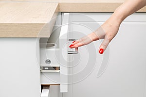 woman& x27;s hand with manicure opens a kitchen cabinet drawer