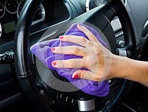 Woman's hand with microfiber cloth polishing wheel of a car