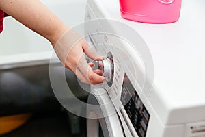A woman& x27;s hand on the mode switch of the washing machine.