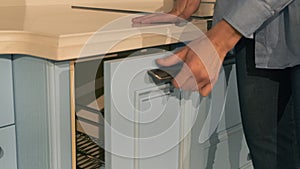 Woman`s hand is open a furniture freezer door on kitchen in modern showroom. Close up of woman at furniture shop