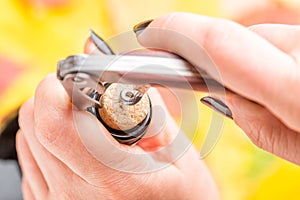 A woman`s hand opens a bottle of white wine with a corkscrew.. Top view.