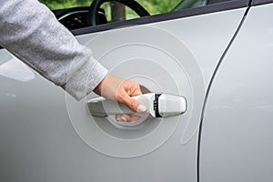 Woman`s hand opens white car door. partial view of woman opening car door. car unlocks. Business woman opening car door, holding