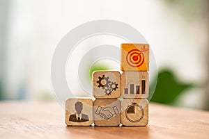 Woman\'s hand organizing wood block with company strategy and action plan icons. Concept of a business growth strategy