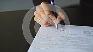 Woman's hand with pen signing document, close up