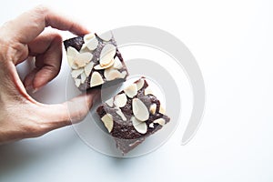 Woman's hand picks chocolate brownie on white background