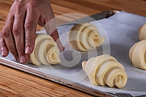 Woman\'s hand placing a croissant on a baking tray to go in the oven