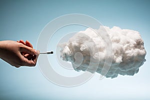 Woman`s hand plugging a wire into a white cloud.