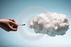 Woman`s hand plugging a wire into a white cloud. photo