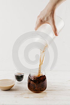 Woman`s hand pouring freshly brewed coffee into glass cup