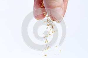 A woman's hand pours dry food for aquarium fish. Macro photography. Isolate