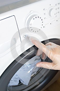 A woman& x27;s hand presses a button on the washing machine.