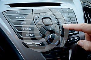 Woman`s hand pressing buttons on a car`s dashboard