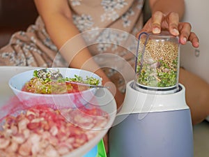 Woman`s hand pressing / securing a blender while it is blending food ingredients at home