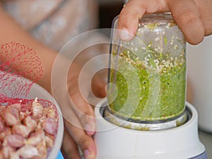 Woman`s hand pressing / securing a blender while it is blending food ingredients at home